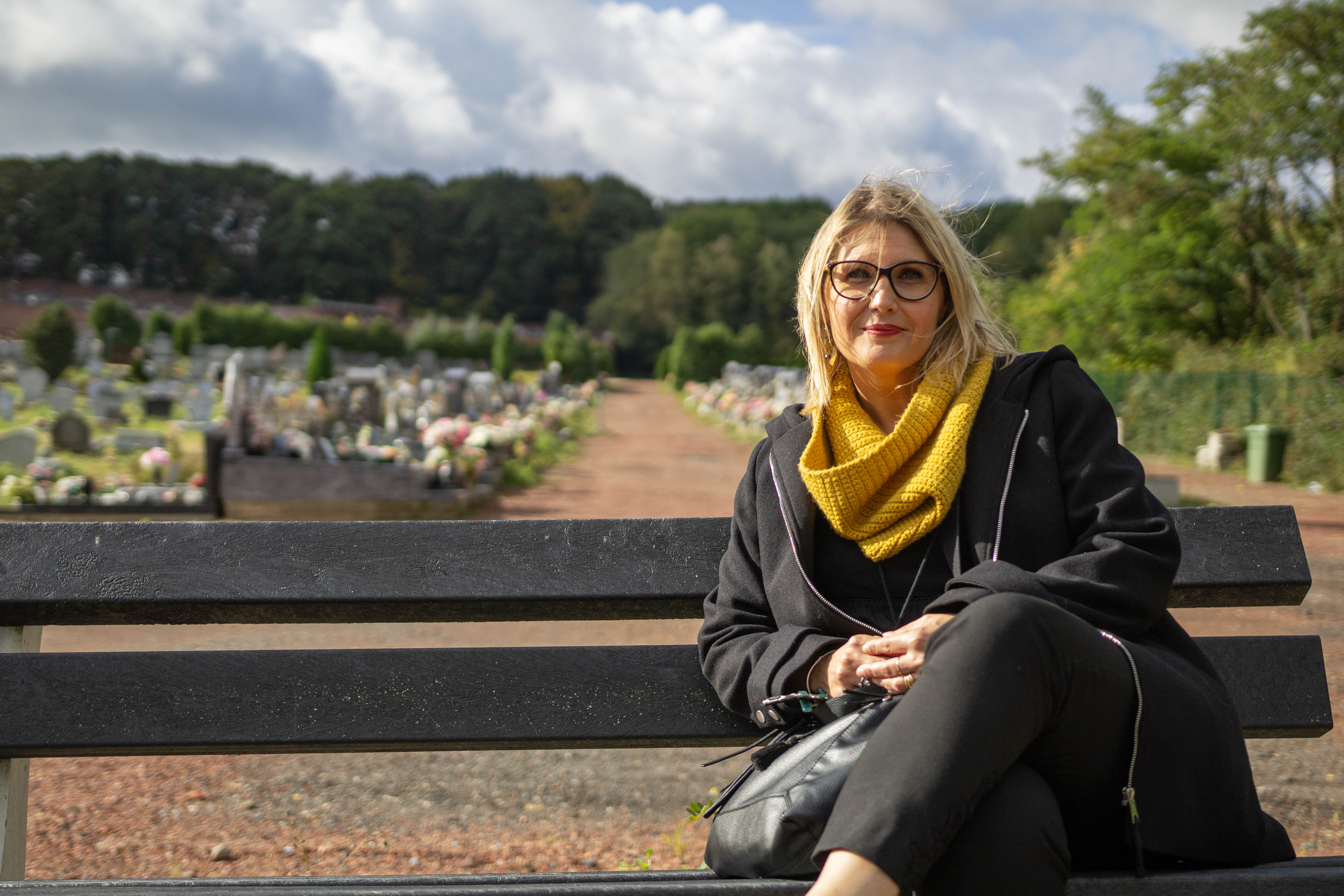 Sabine Roberty, assise sur un banc du cimetière de la Bergerie à Seraing