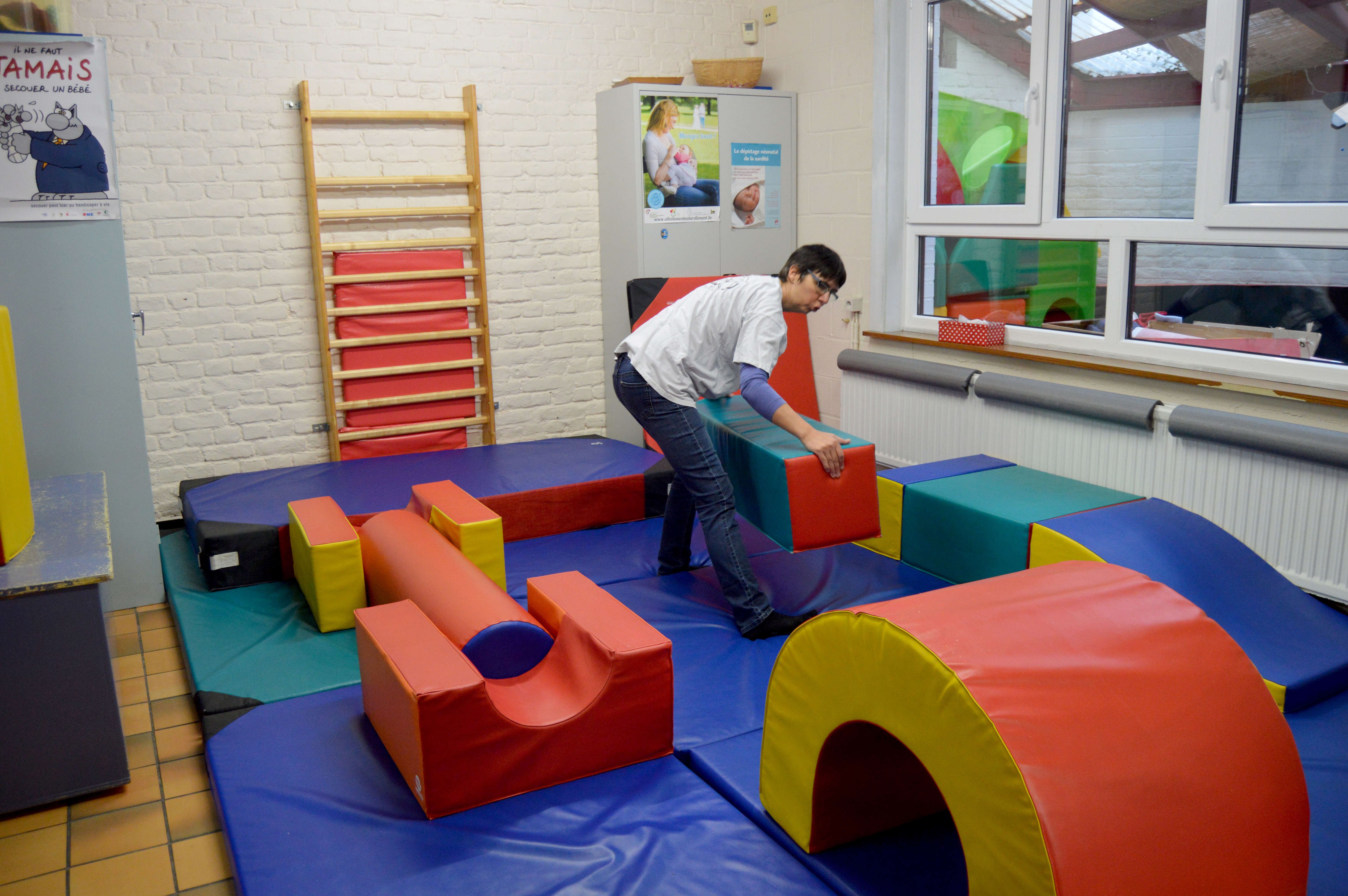 Une bénévole en train de préparer la pièce des enfants. Des toboggans, des tapis...