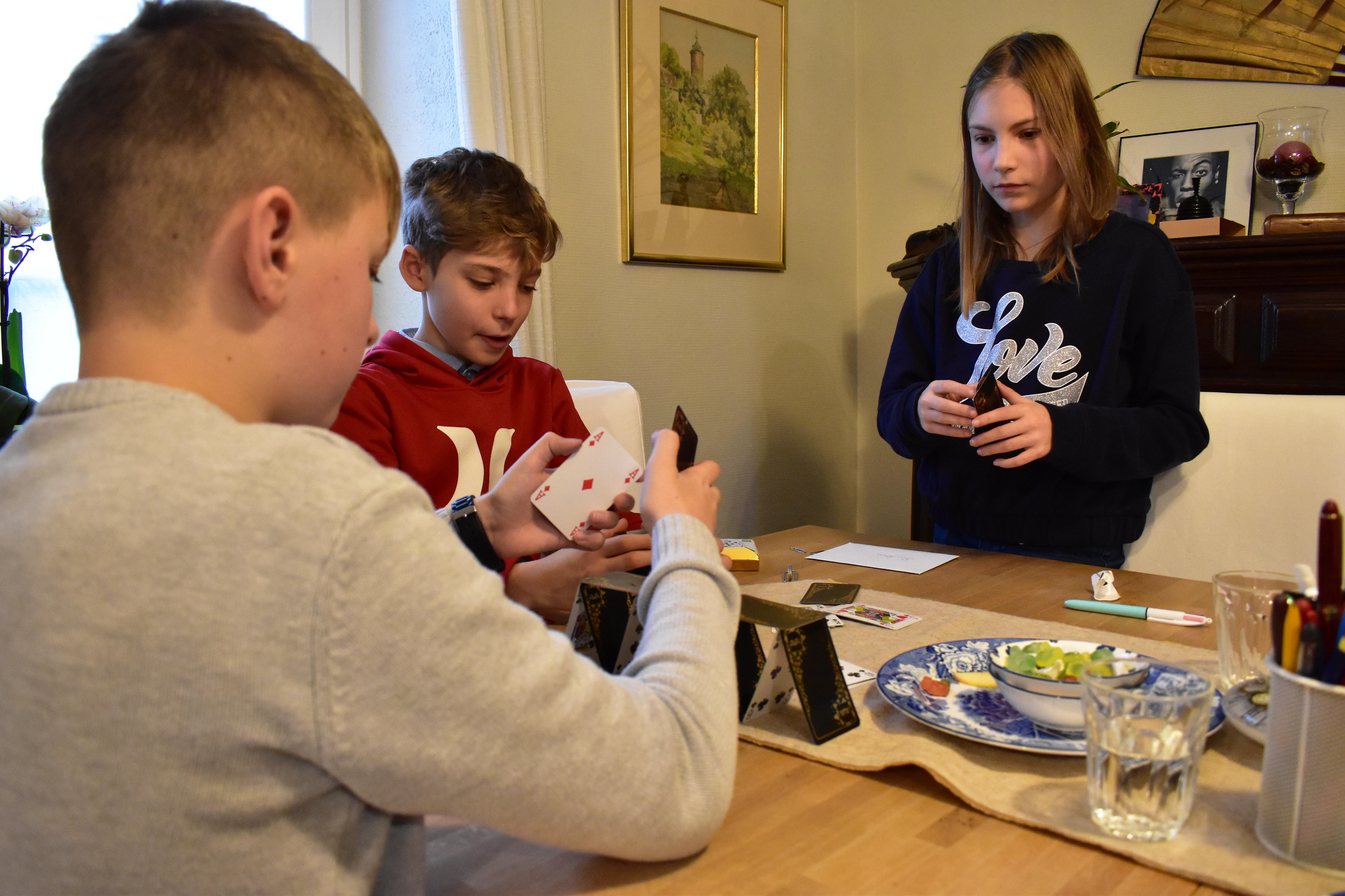 3 jeunes faisant un chateau de cartes