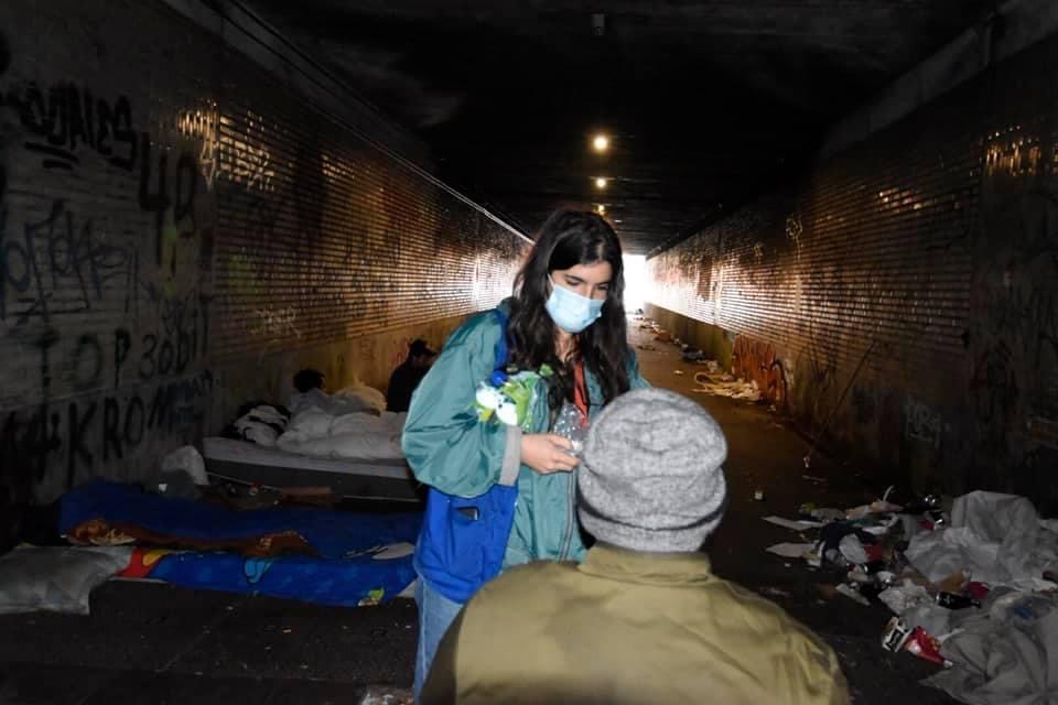 Lisa en train de donner un bouteille d’eau a un SDF.