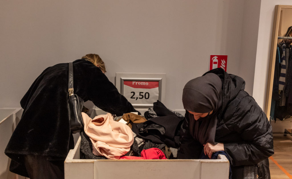 Dames fouillant un bac à la recherche de vêtements.