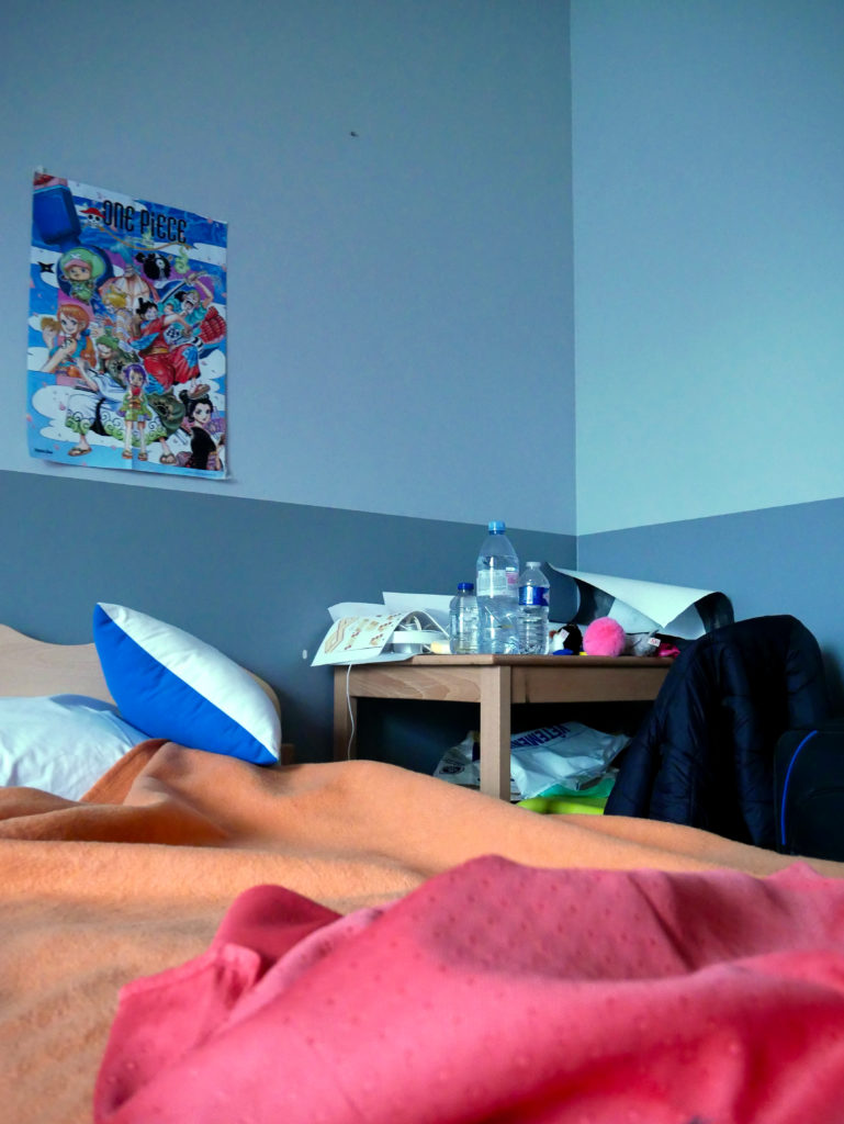 Chambre d'un patient en désordre avec un poster de "One Piece". 