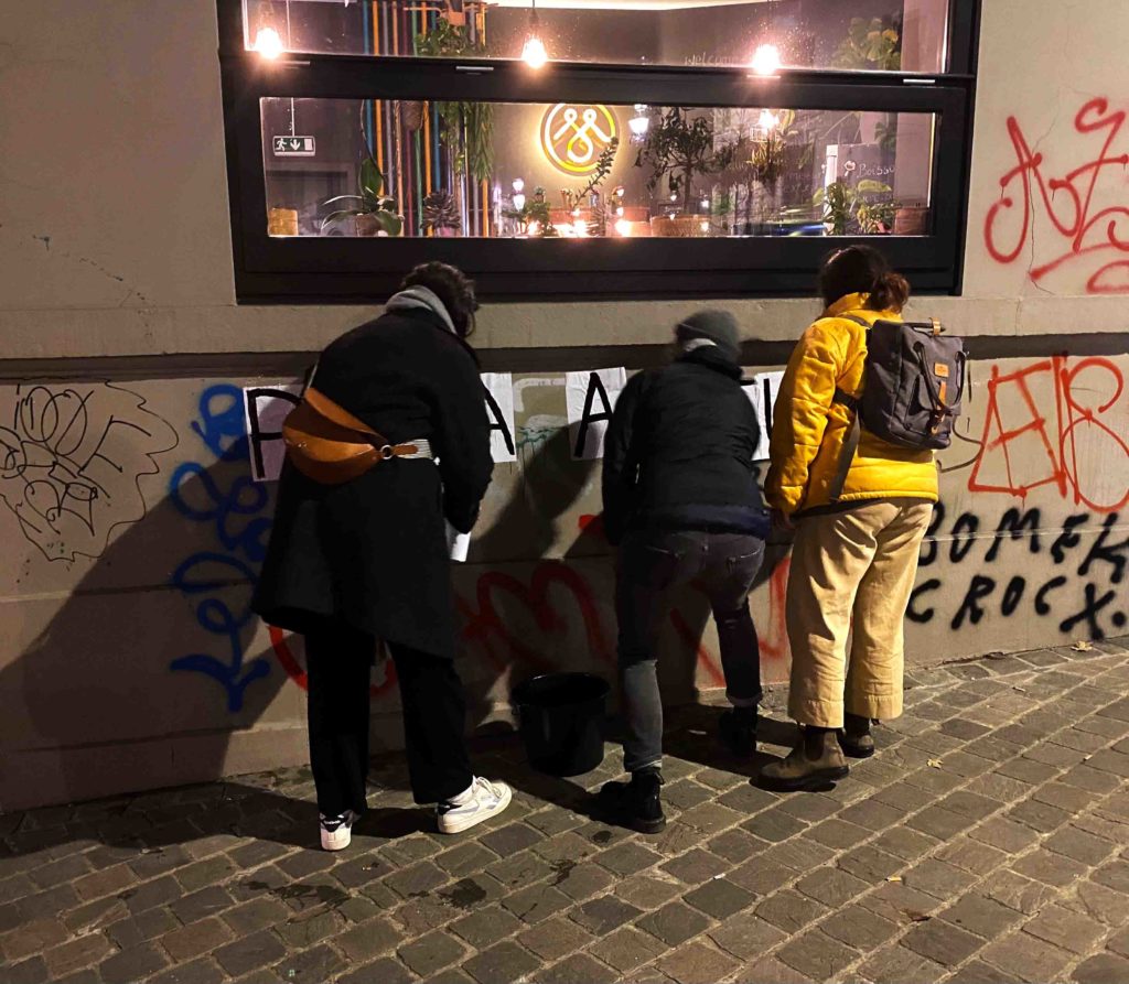 Le groupe de colleuses de Saint-Gilles collent leur slogan sur le mur d'un café de Saint-Gilles.