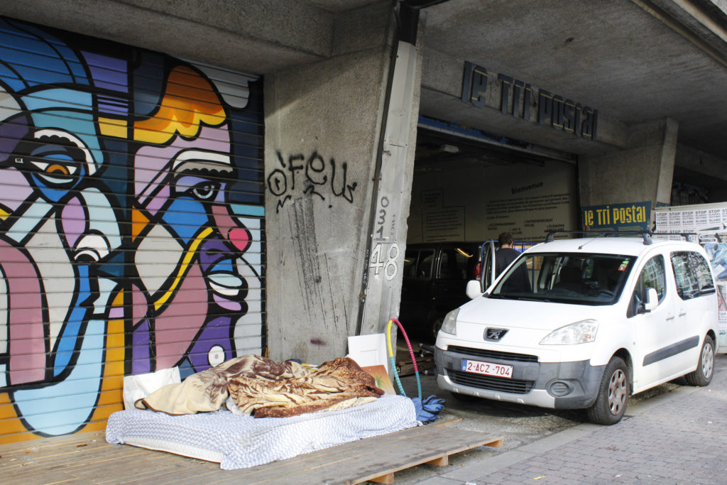 L'entrée du Tri Postal, un matelas par terre et une voiture.