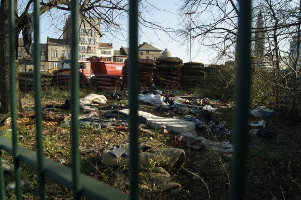 derrière des barrières, des restes de matelas et vêtements jonchent le sol