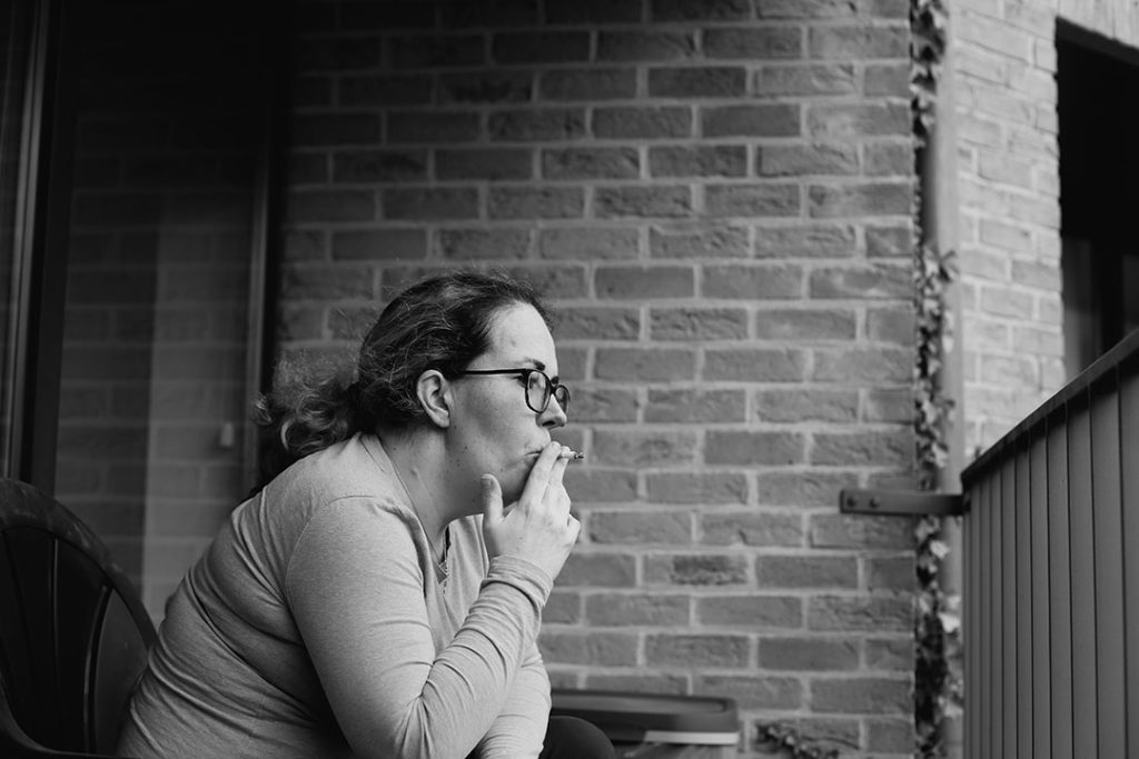 Marie fume un cigarette sur le balcon.